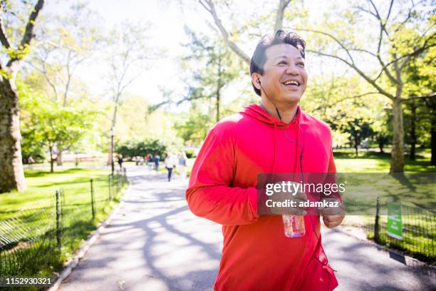 madura hombre hispano jogging en central park - new york personas fotografías e imágenes de stock