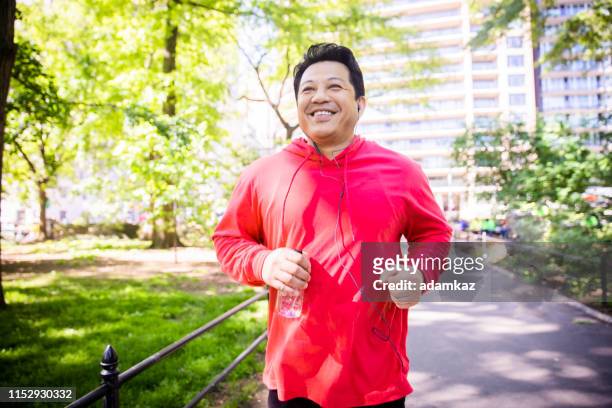 reifer hispanics jogging im central park - run shirt stock-fotos und bilder