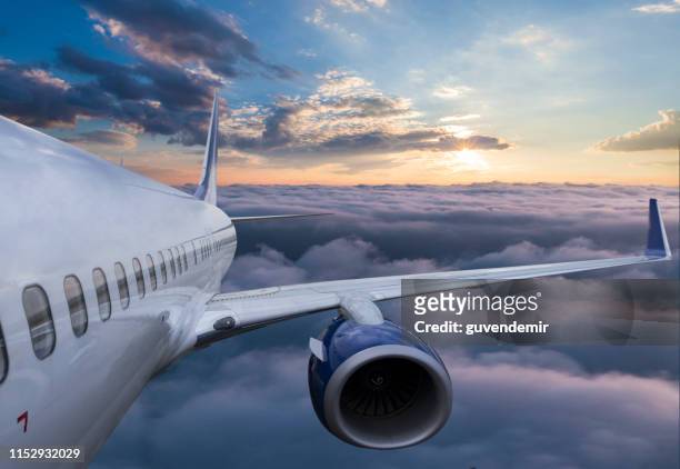 body of an airplane flying through clouds at sunset - plane wing stock pictures, royalty-free photos & images