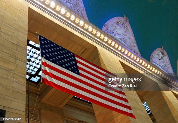 american national flag hangs inside the grand central terminal in manhattan, new york city - grand central tours stock pictures, royalty-free photos & images