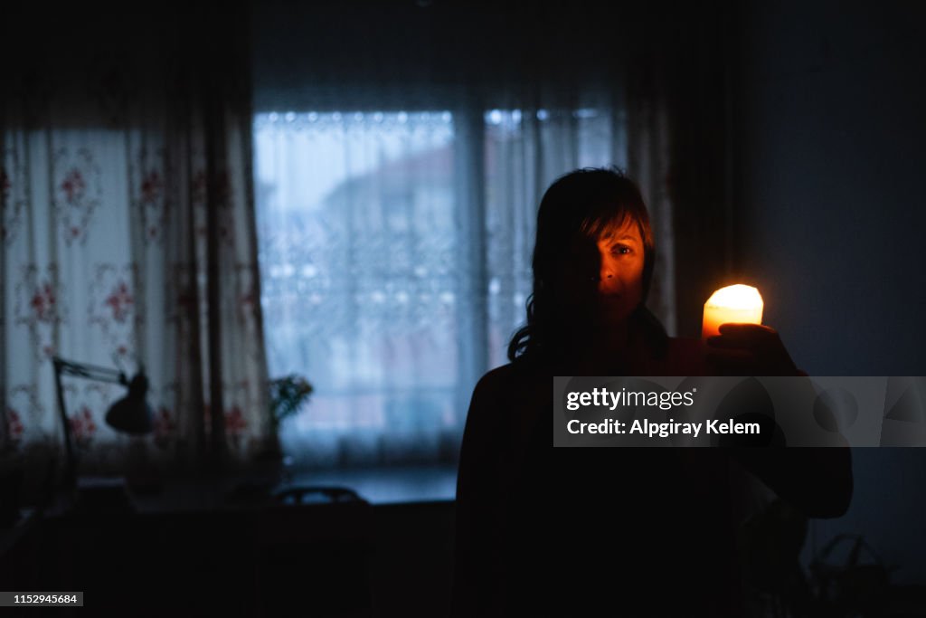 Woman with candle at home because of power cut