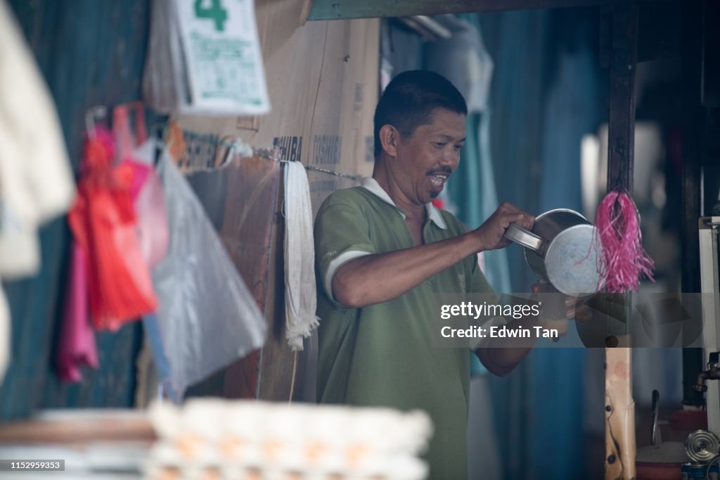 A malaysian hawker owner making tea for his customer by pulling the tea and pouring to the drinking glass which local called it "teh tarik"