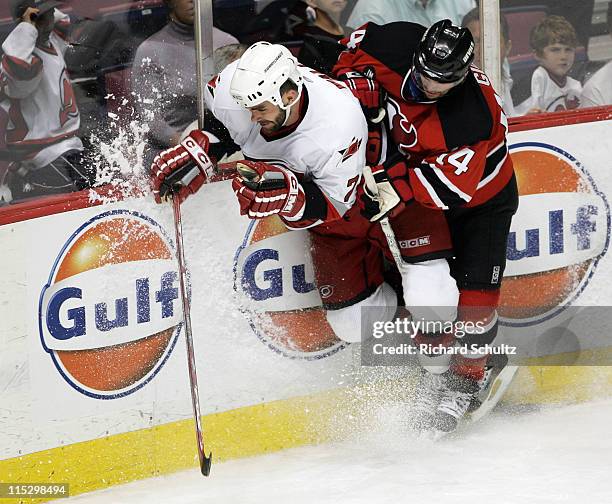 Carolina Hurricanes' Niclas Wallin is checked by Brian Gionta of the New Jersey Devils during the third period of game three in the Eastern...