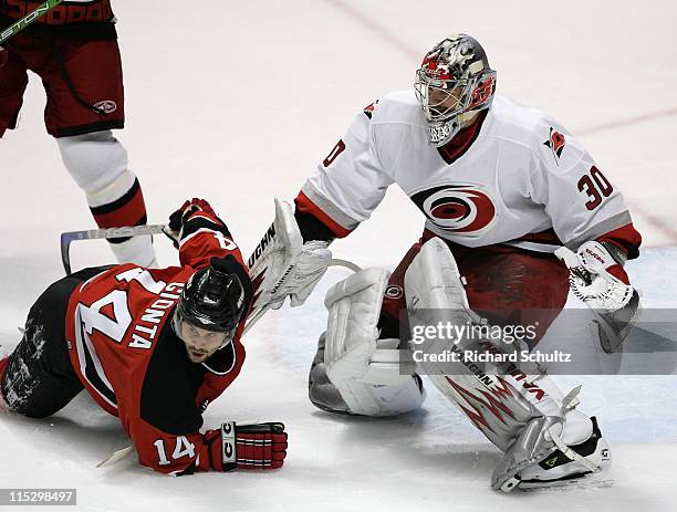 Carolina Hurricanes' goaltender Cam Ward keeps his eye on the puck as Brian Gionta of the New Jersey Devils goes down in front of the crease during...