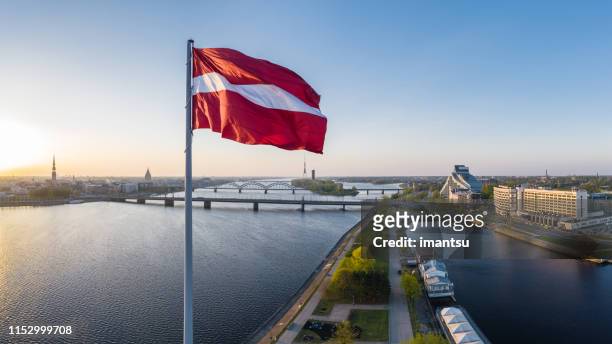 closeup of the huge flag of latvia haning above the ab dam in riga - riga stock pictures, royalty-free photos & images
