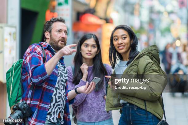 group of multi-ethnic tourist friends checking smart phone for directions - povo do sudeste asiático imagens e fotografias de stock