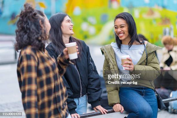 group of multi-ethnic friends drinking hot drink in street - hot filipina women stock pictures, royalty-free photos & images