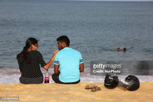 Young couple sitting by the seashore at Thalaiyadi Beach in Jaffna, Sri Lanka.
