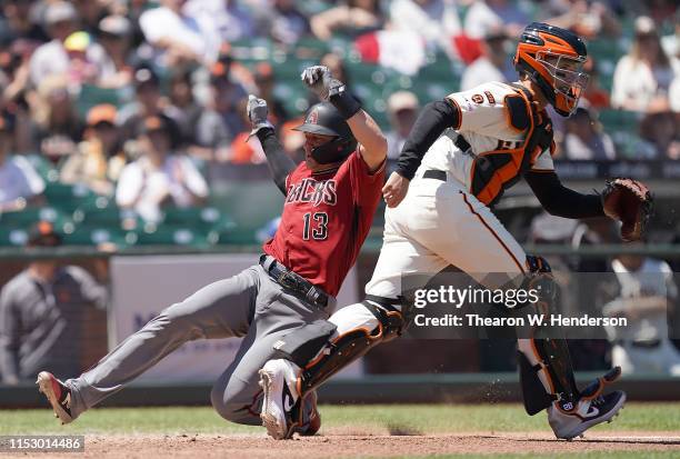 Nick Ahmed of the Arizona Diamondbacks scores ahead of the throw to catcher Buster Posey of the San Francisco Giants in the top of the fifth inning...