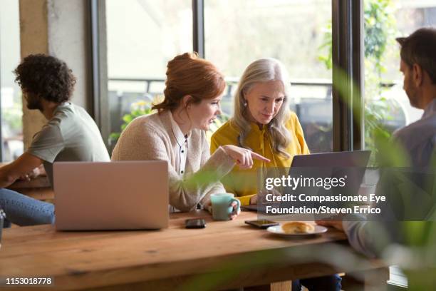 creative businesswomen having informal meeting in modern open plan office - menselijke leeftijd stockfoto's en -beelden