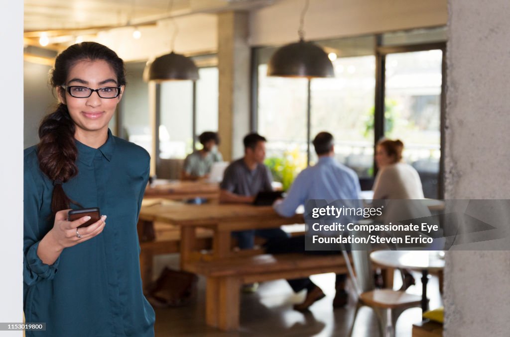 Businesswoman using cell phone in open plan office