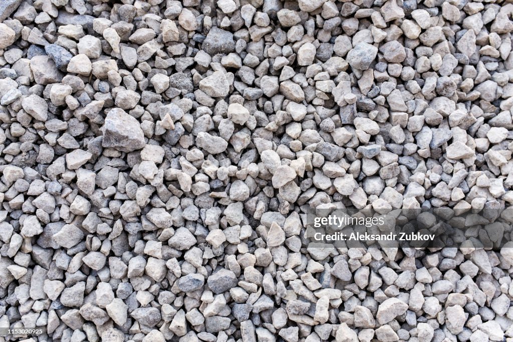 Mound of granite gravel, stones, crushed stone close-up. Rough seamless texture, construction material background.