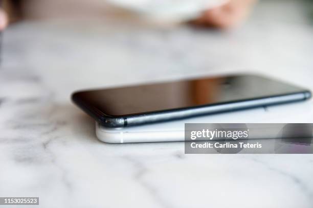 two mobile phones on a table wirelessly charging from each other - smart phone on table stock pictures, royalty-free photos & images