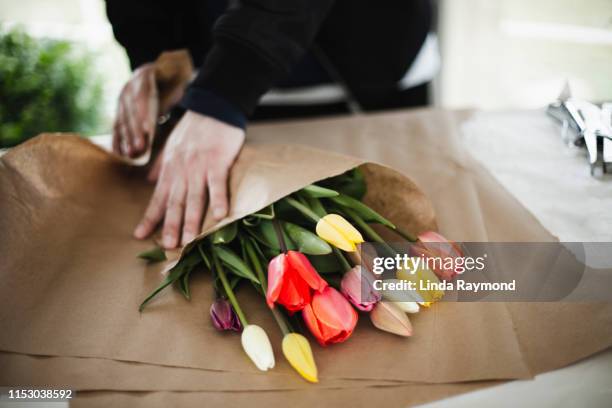 mazzo di tulipani arcobaleno in un involucro di carta marrone - bouquet foto e immagini stock
