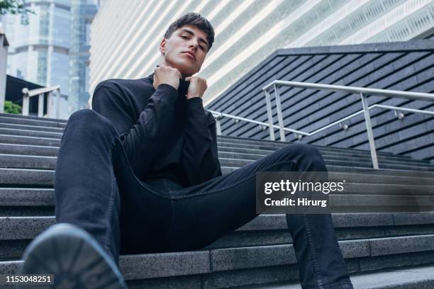 knappe man in zwarte kleding zittend op trappen - zwarte spijkerbroek stockfoto's en -beelden