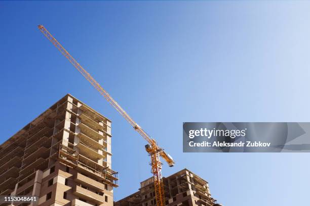 industrial crane and unfinished multi-storey brick concrete building on the construction site against the sky. the concept of long-term construction, freezing. - block flats stock pictures, royalty-free photos & images