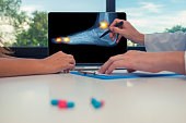 Doctor showing a x-ray of a foot and pain on the toes and ankle on a laptop to a woman patient. Pills on the desk