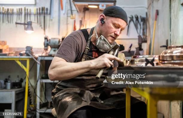 manual worker wearing a protective apron checking the brass details in the workshop - brocade stock pictures, royalty-free photos & images