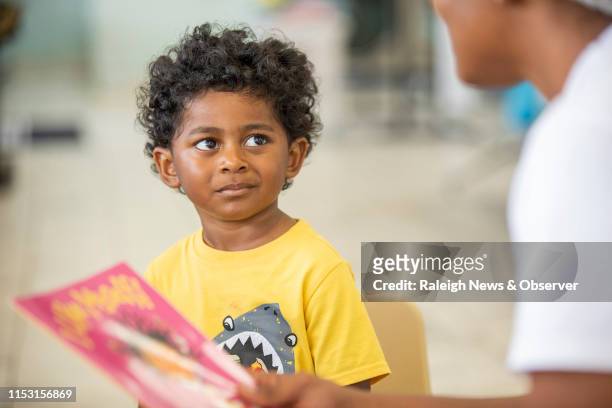 Elías Benítez, de 3 años, escucha a Nadiah Porter, gerente de alianzas comunitarias para Book Harvest, mientras le lee durante un programa llamado...