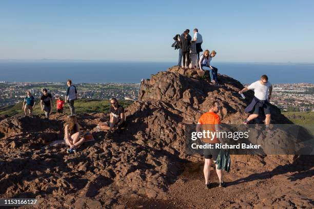 Walkers enjoy summer evening sunshine on the summit of Arthur's Seat in Holyrood Park, overlooking the city of Edinburgh and the Firth of Fourth...