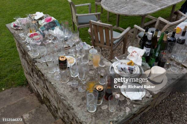 The aftermath debris of glasses, bottles, cans and plates, the morning after a 50th birthday party, spread around the garden in the Herefordshire...