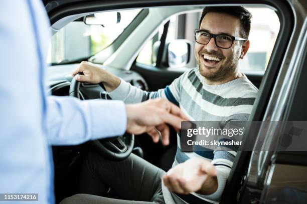 ung lycklig man får nya bil nycklar i ett showroom. - handing over keys bildbanksfoton och bilder