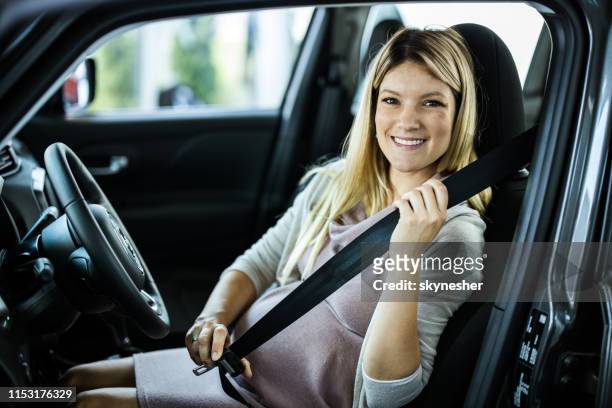 happy pregnant woman fastening her seatbelt in a car. - belt imagens e fotografias de stock