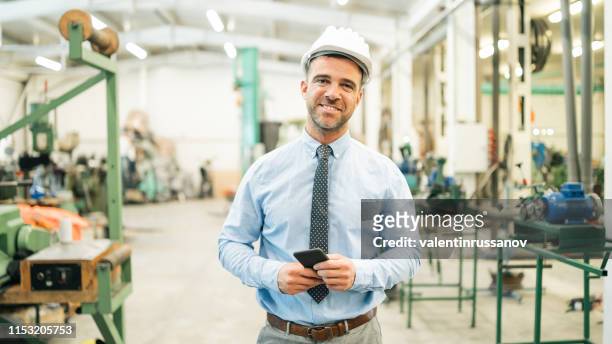 zakenman wandelen in de fabriek, kijkend naar de camera - factory owner stockfoto's en -beelden