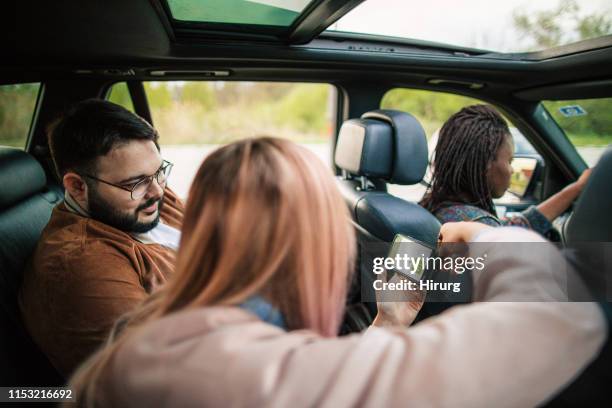 friends using mobile app at the car - back seat stock pictures, royalty-free photos & images