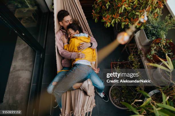 entspannende momente in einer hängematte - couple balcony stock-fotos und bilder