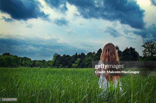 young girl in field with storm clouds - murfreesboro stock-fotos und bilder