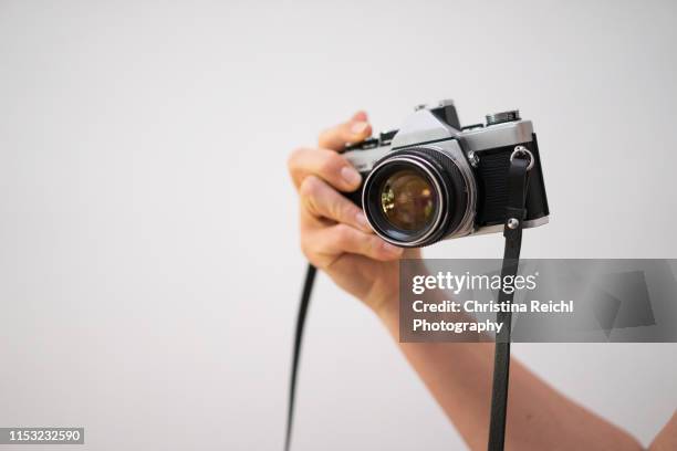 woman holding a vintage camera in hand - kamera stock-fotos und bilder