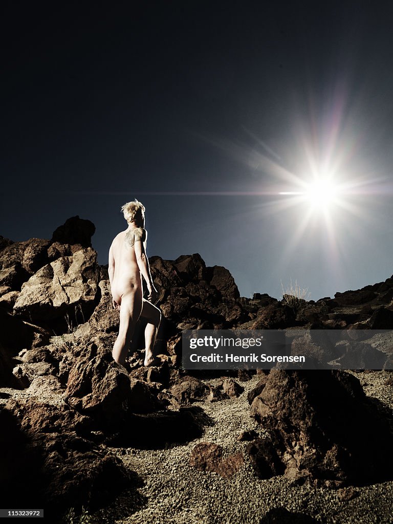Young naked male standing in vulcanic desert