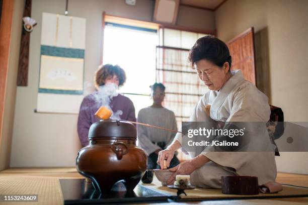 japanischer tee-meister flüstert matscha-tee - tea ceremony stock-fotos und bilder