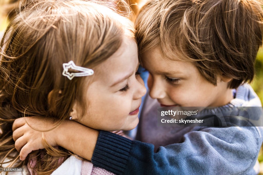 Close up of affectionate kids embracing outdoors.
