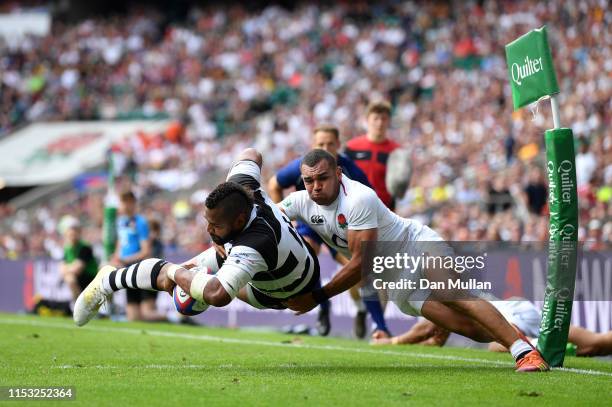 Taqele Naiyaravoro of the Barbarians dives over to score a try as he is tackled by Joe Marchant of England during the Quilter Cup match between...