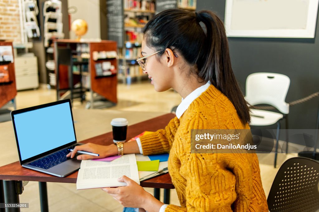Young woman working on her laptop in the library
