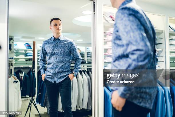 mann versucht hemd in einem geschäft - umkleidekabine stock-fotos und bilder