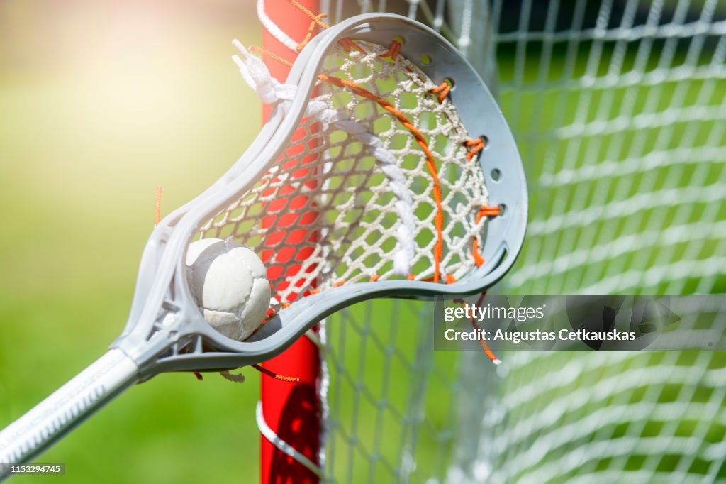Abstract view of a lacrosse stick scooping up a ball. Sunny day