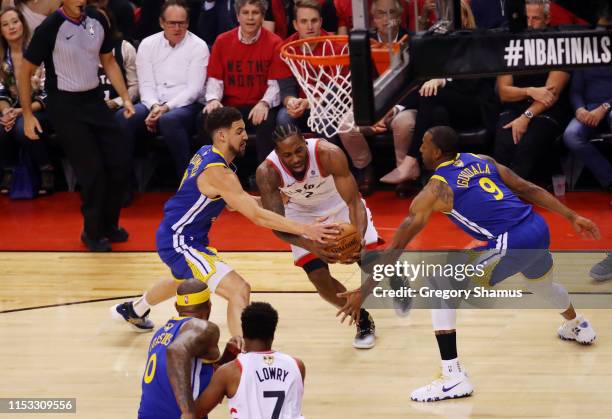 Kawhi Leonard of the Toronto Raptors drives to the basket against Shaun Livingston and Andre Iguodala of the Golden State Warriors in the first half...