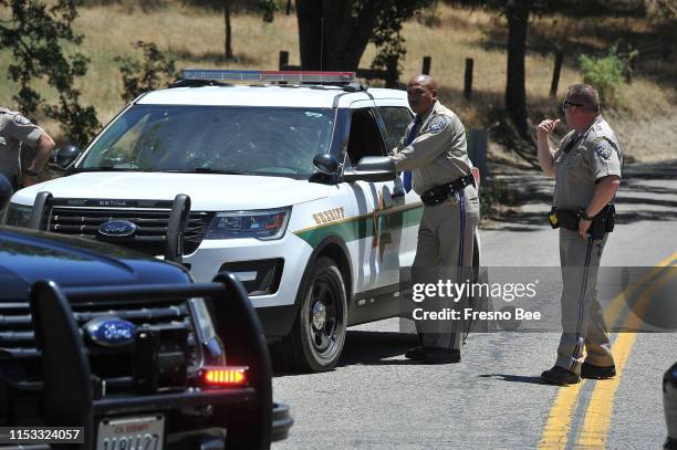 California Highway Patrol officers talk to a Fresno County Sheriff's deputy at a roadblock at Burroughs Valley and Tollhouse roads near where a...