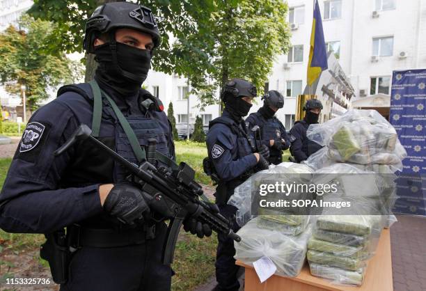 Police officers stand on guard next to bags of cocaine, which were seized during a special police operation, at a press conference of the National...