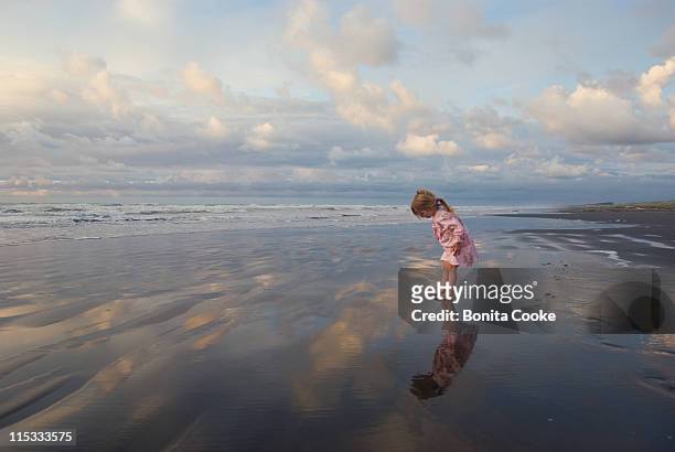 little girl looking at her reflection at beach - wet girl stock-fotos und bilder