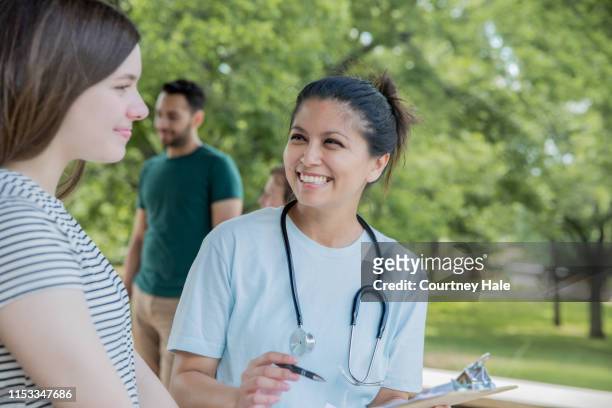 nurse talking to teenager during an event with free healthcare - film and television screening stock pictures, royalty-free photos & images
