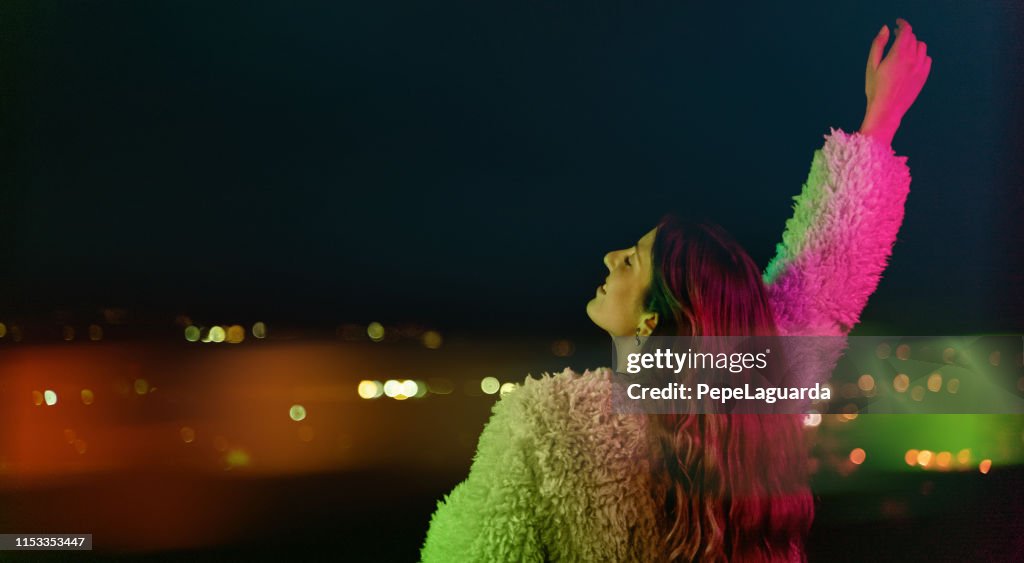 Jovencita mirando luces de la ciudad bajo la luz colorida