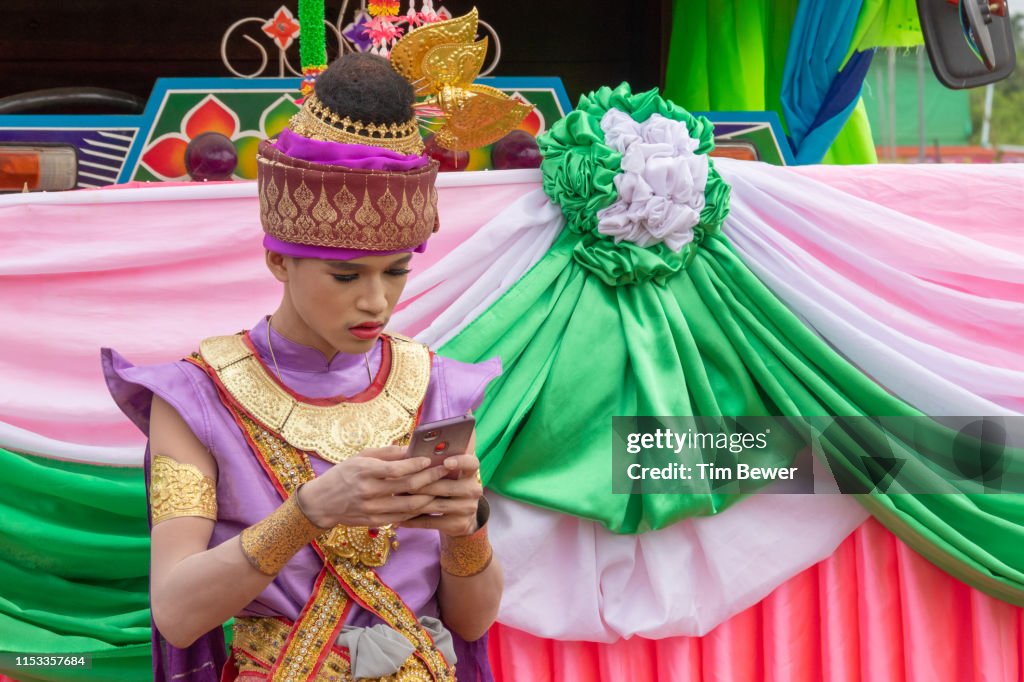Man in traditional Thai clothes using his phone.