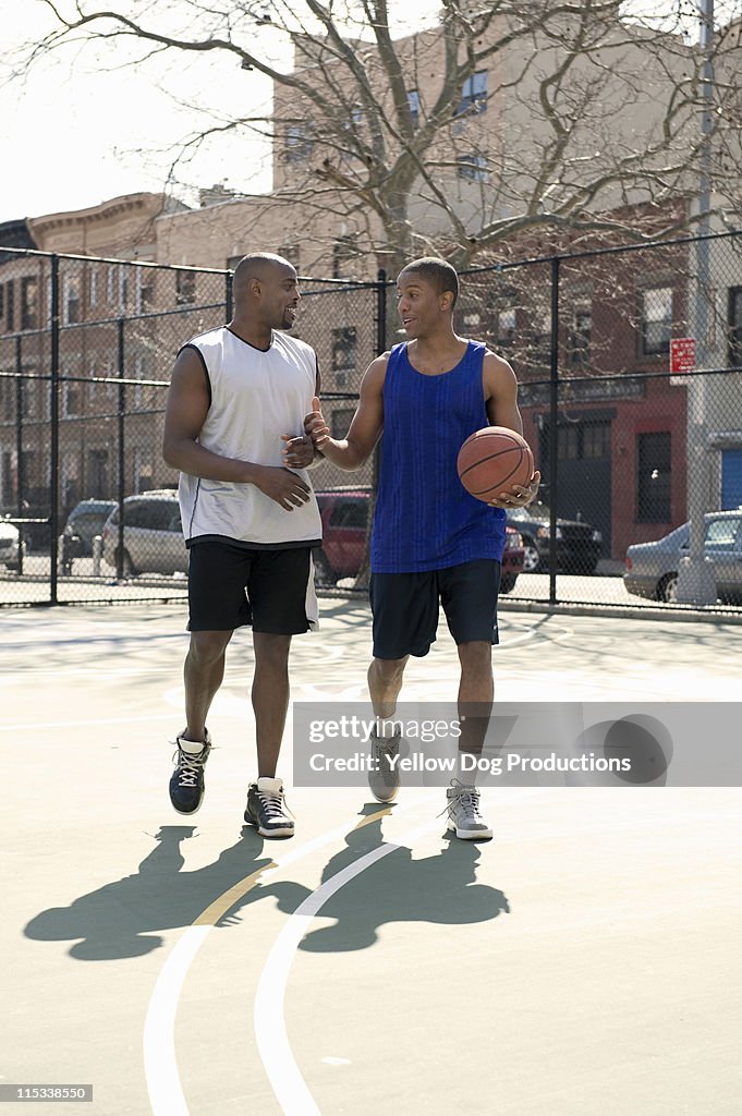 Two Male Adults Walking on Basketball Court