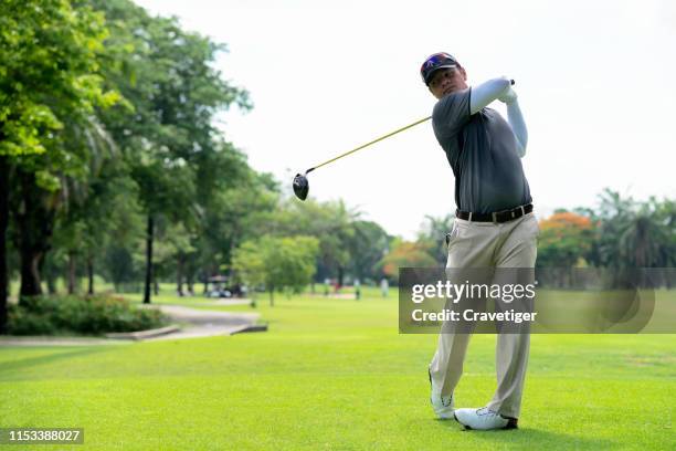 golfer hitting golf shot with club on course while on summer vacation. golfer swings his driver off the tee. - golf swing imagens e fotografias de stock