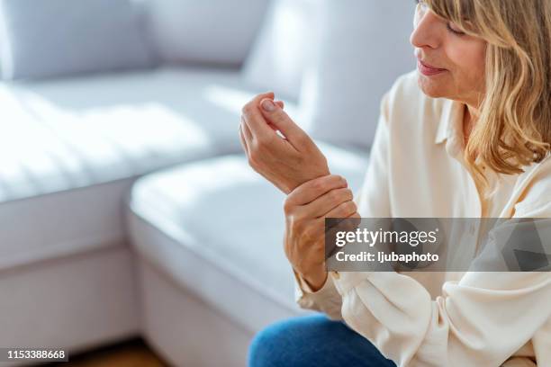 在宅で手に痛みに苦しむ先輩女性 - arm pain ストックフォトと画像