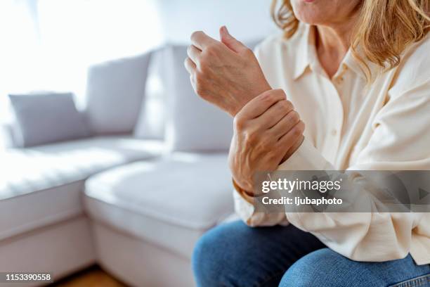 senior vrouw wrijven haar pols en arm die lijden aan reuma - artrose stockfoto's en -beelden